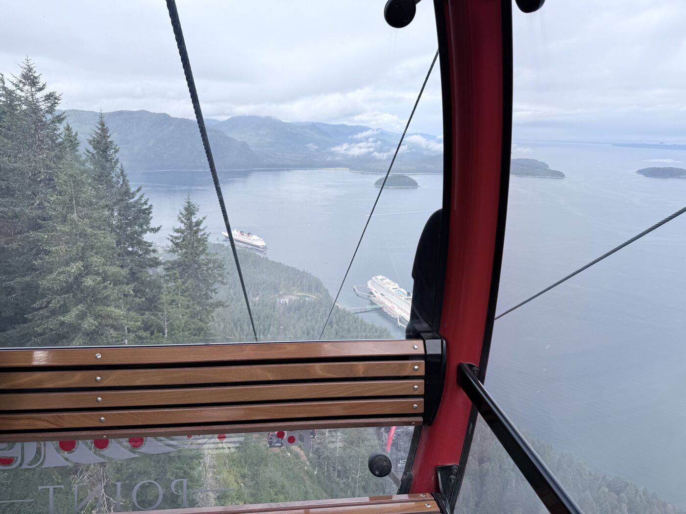View from a gondola cabin window looking down over Icy Strait Point's two cruise ship piers and the strait beyond