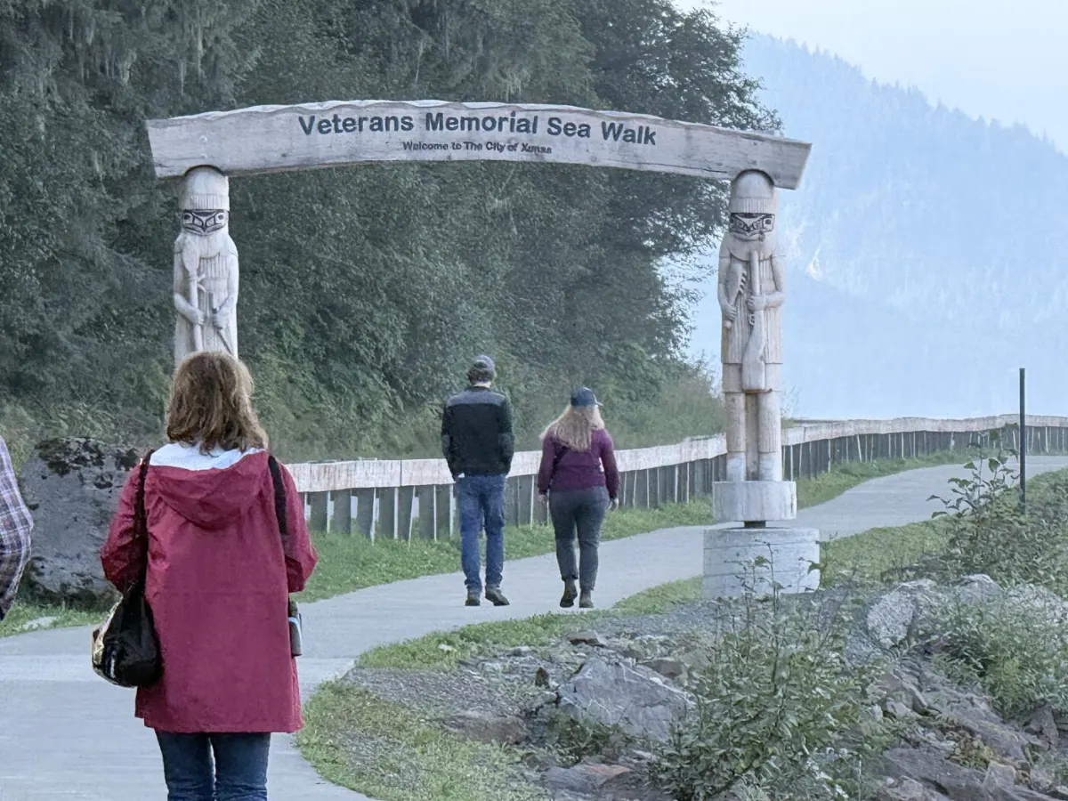 The carved totem archway marking the start of the Veterans Memorial Sea Walk, with walkers passing underneath